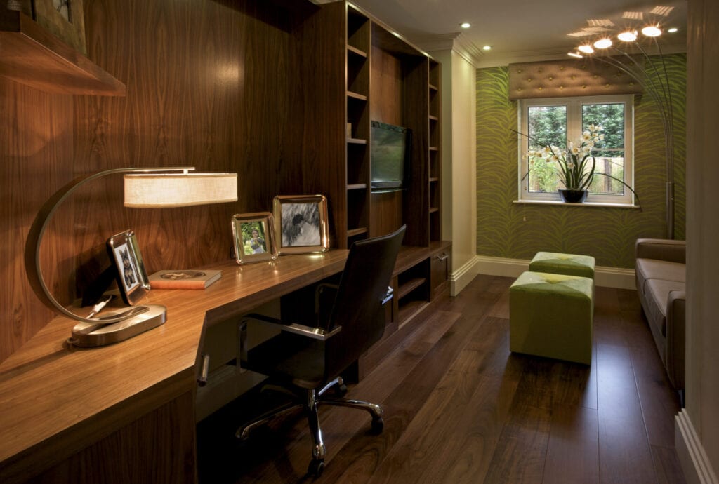 Une belle salle de bureau lambrissée de bois foncé dans un appartement de luxe. Le parquet est en noyer massif. Il s'agit d'une maison témoin d'un projet de luxe et elle a été meublée par un architecte d'intérieur. Deux poufs cubes verts sont éclairés par une lampe d'angle inhabituelle. Une grande lampe de bureau éclaire le plateau du bureau. Toutes les images encadrées sont incluses dans mon portfolio iStock.